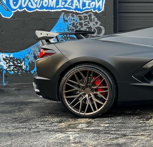 A black sports car is parked in front of a building with graffiti on it.