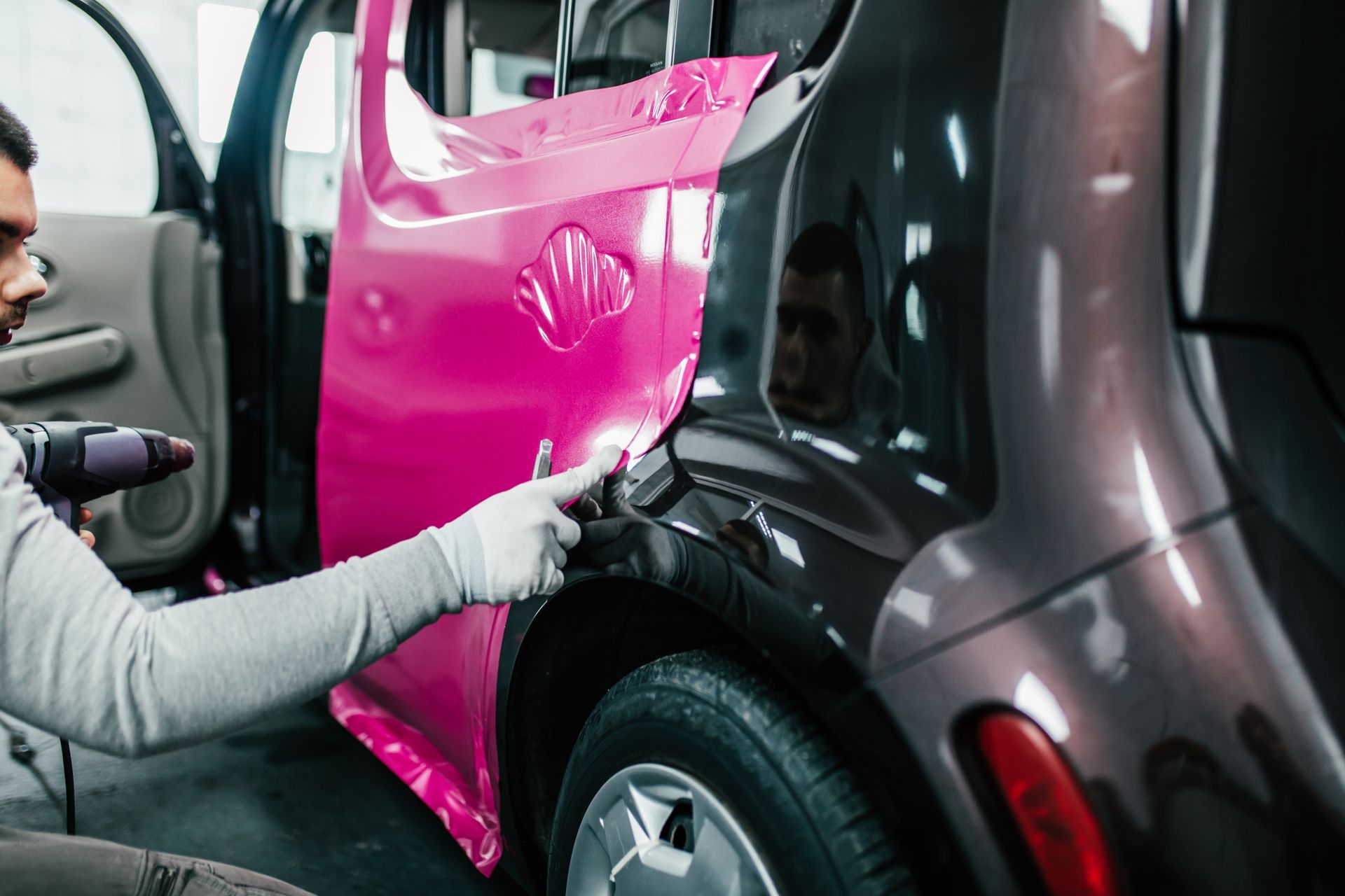a man is polishing the hood of a car with a machine .