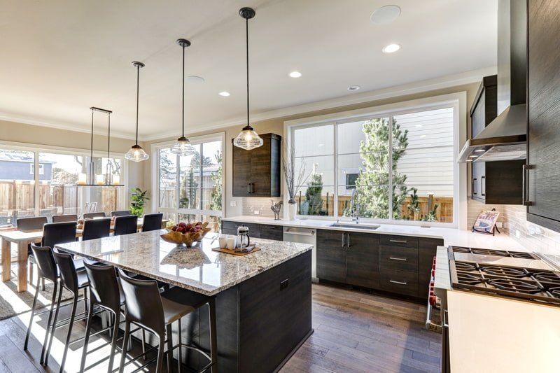 black wood and white granite counter top kitchen with island and hanging lights