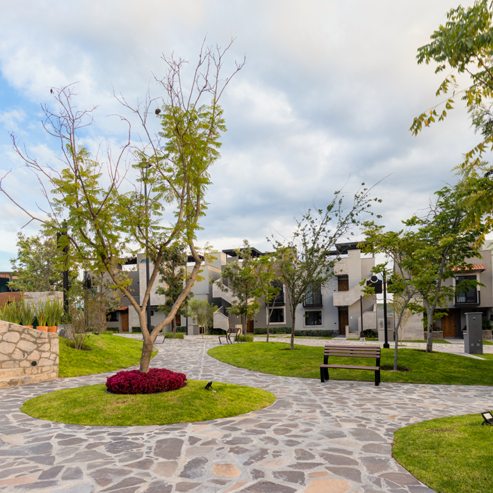 Un camino de piedra rodeado de árboles y césped frente a un edificio.