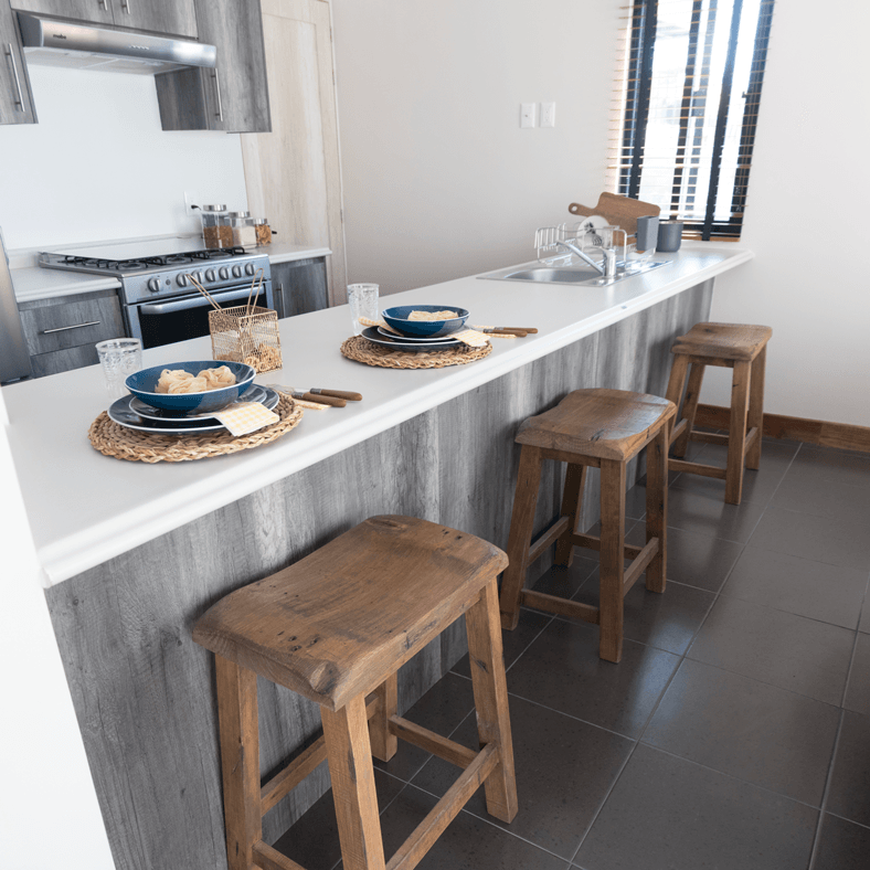 Una cocina con una encimera larga y taburetes de madera.