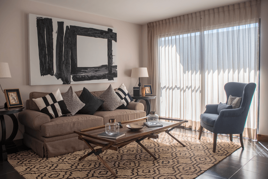 Una sala de estar con un sofá, una silla, una mesa de café y un cuadro en la pared.