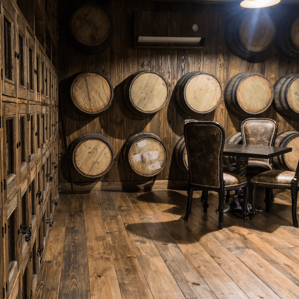 Una habitación llena de barriles de madera y una mesa y sillas.