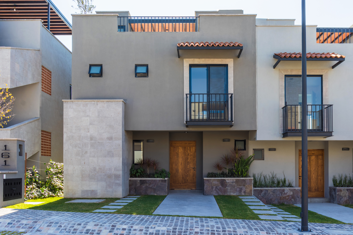 Una casa con balcón y entrada para auto al frente.