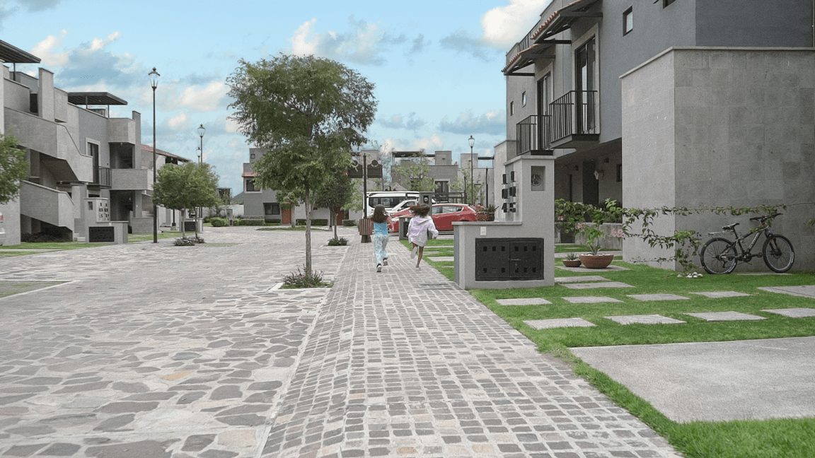 Un grupo de personas camina por una calle adoquinada en una zona residencial.