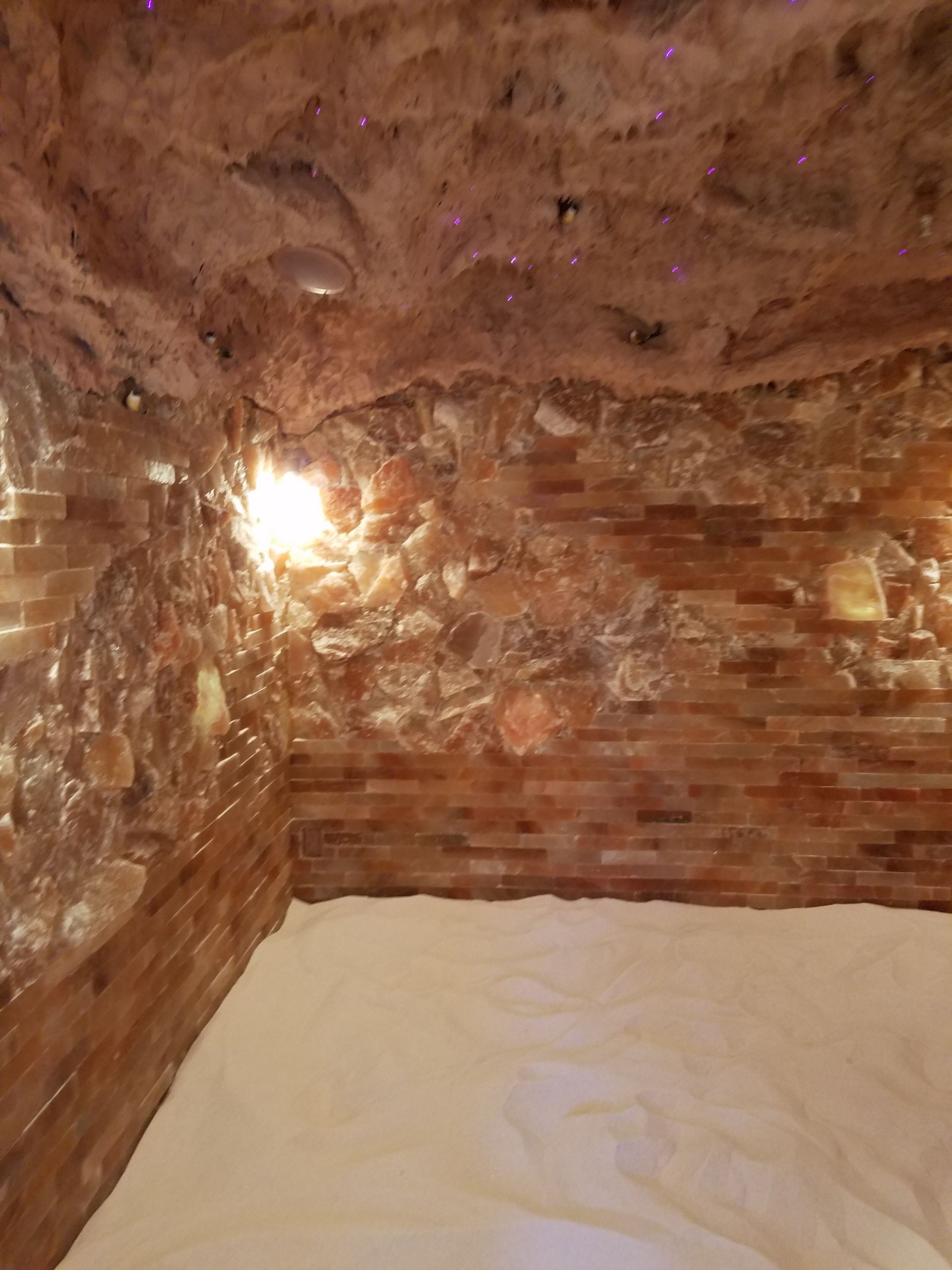 There is a bed in the middle of a room with a brick wall.