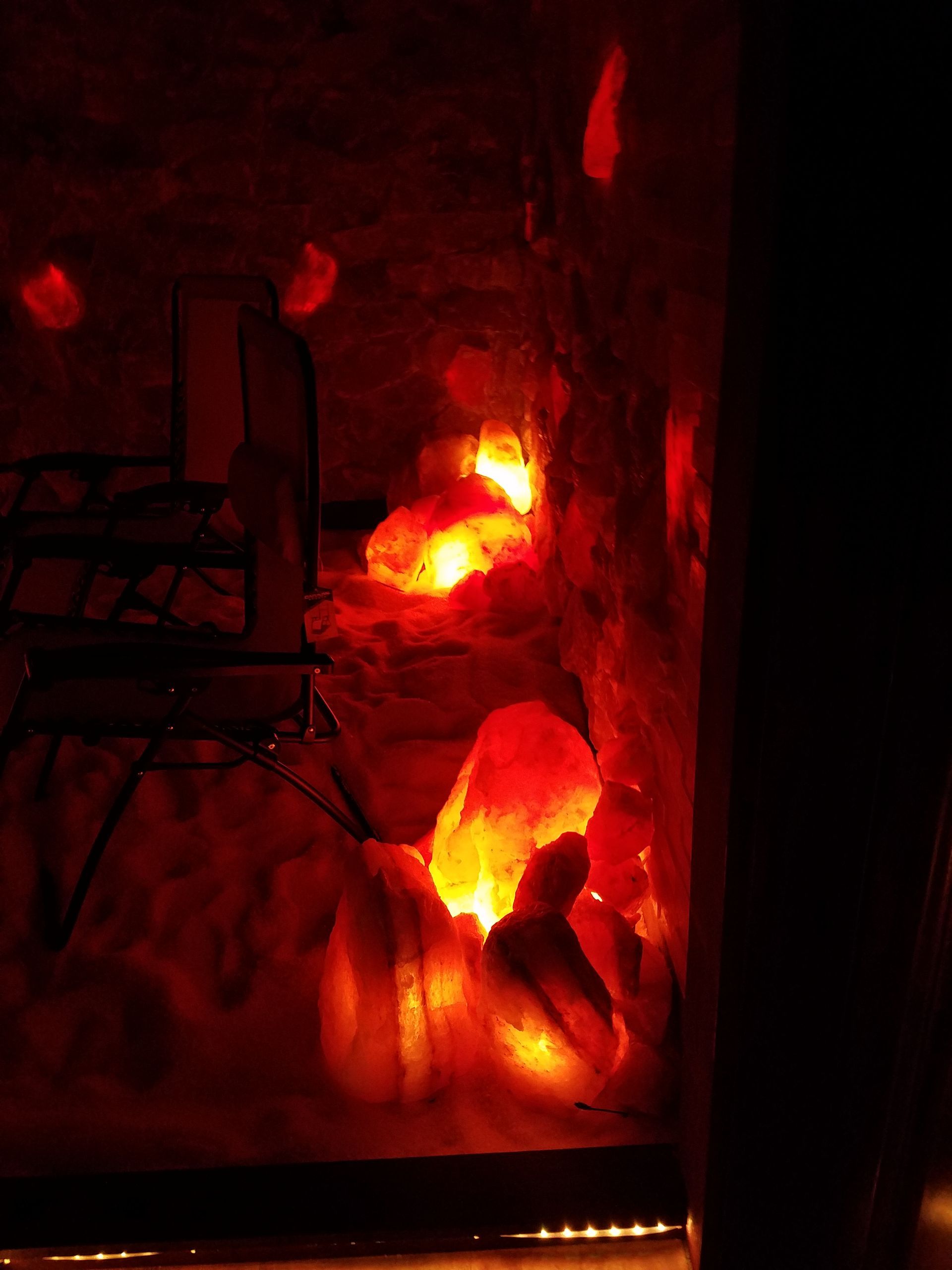A fire is lit up in a dark room with a chair in the background.