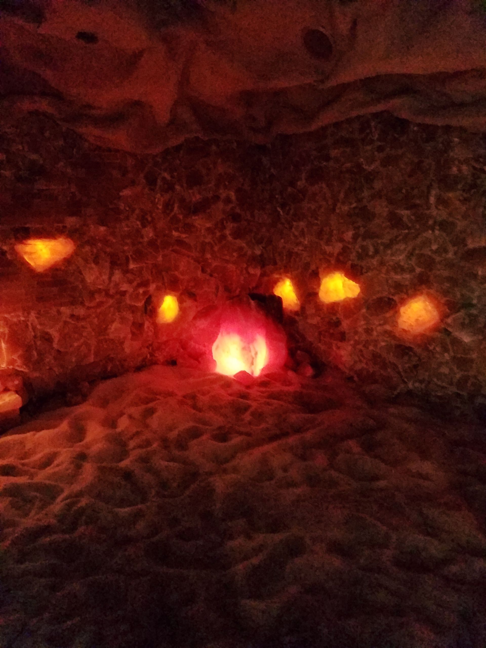 A person is laying in a cave with candles.