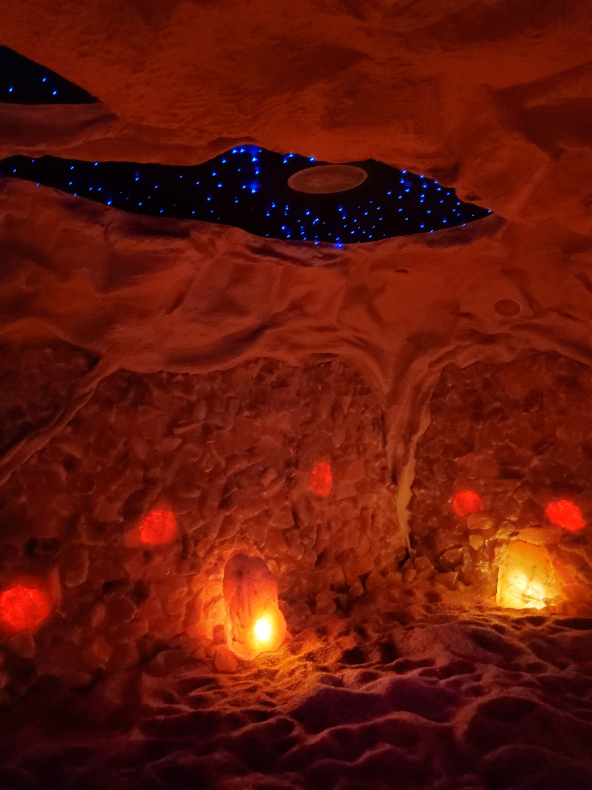 Cave-like interior with reddish walls and glowing orange lights, a starry blue ceiling peeks through.