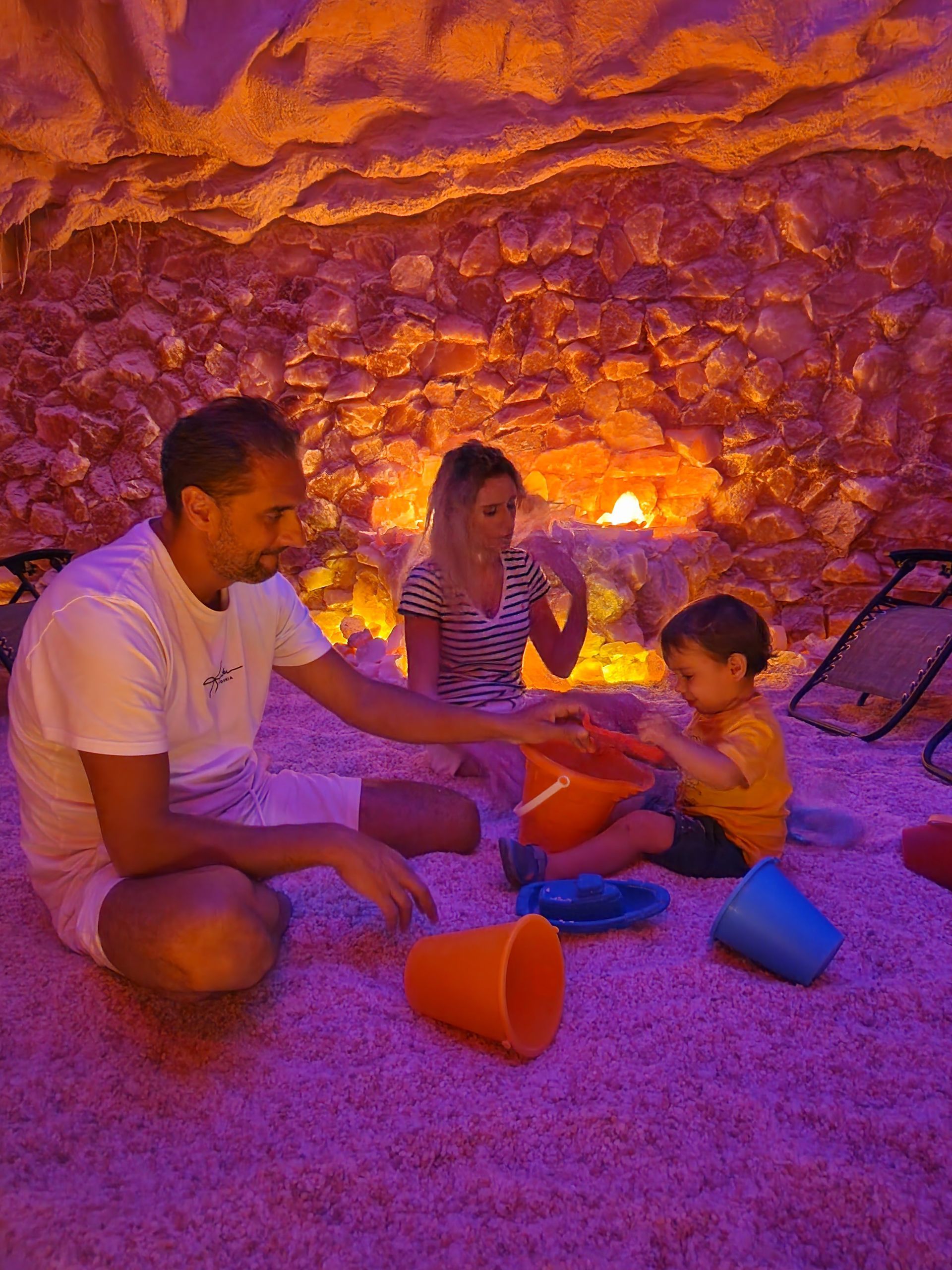 A man and a woman are playing with a child in a salt cave.