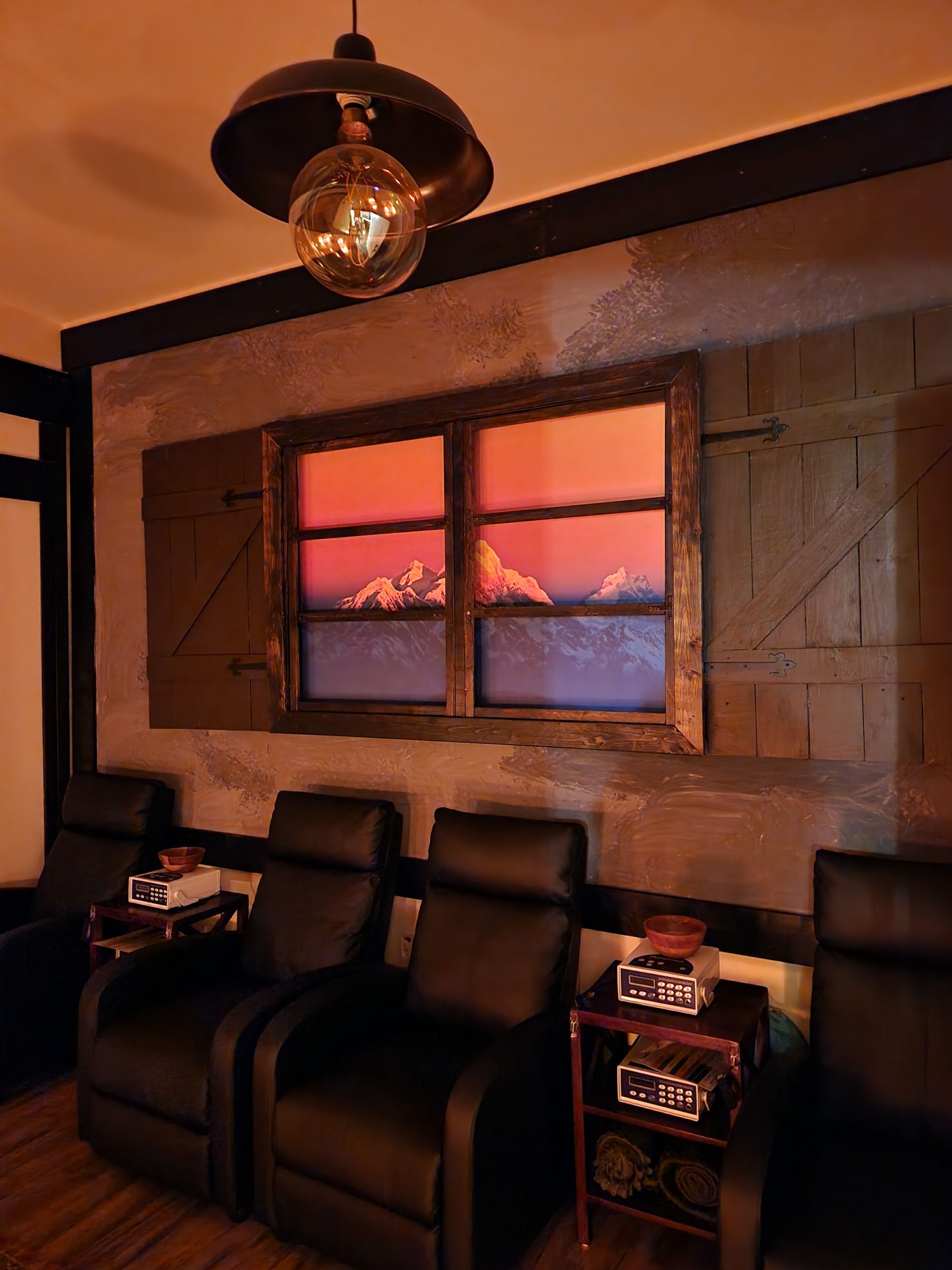 A room with three chairs and a window with a picture of mountains on it.