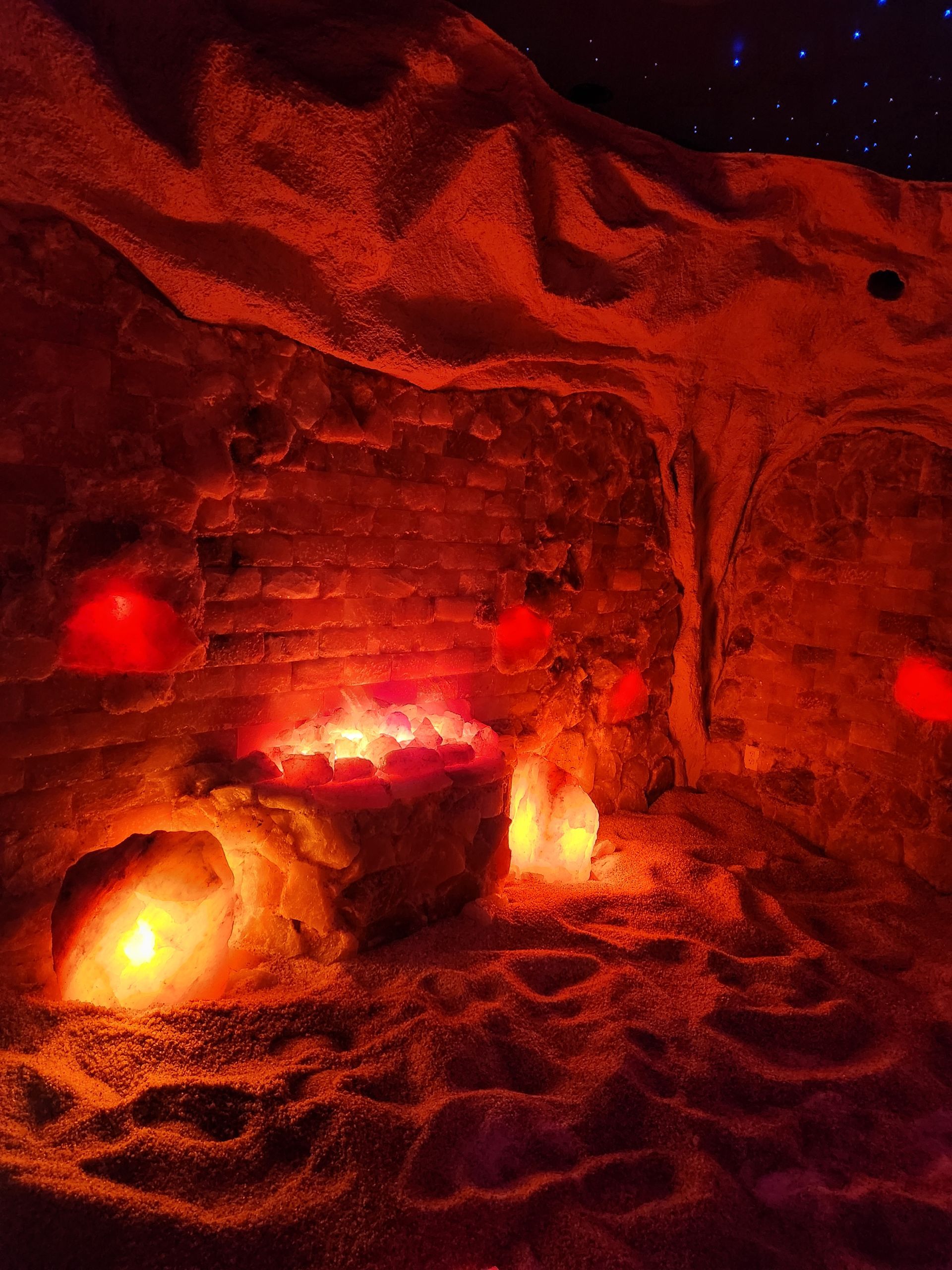 A cave filled with rocks and candles is lit up at night.