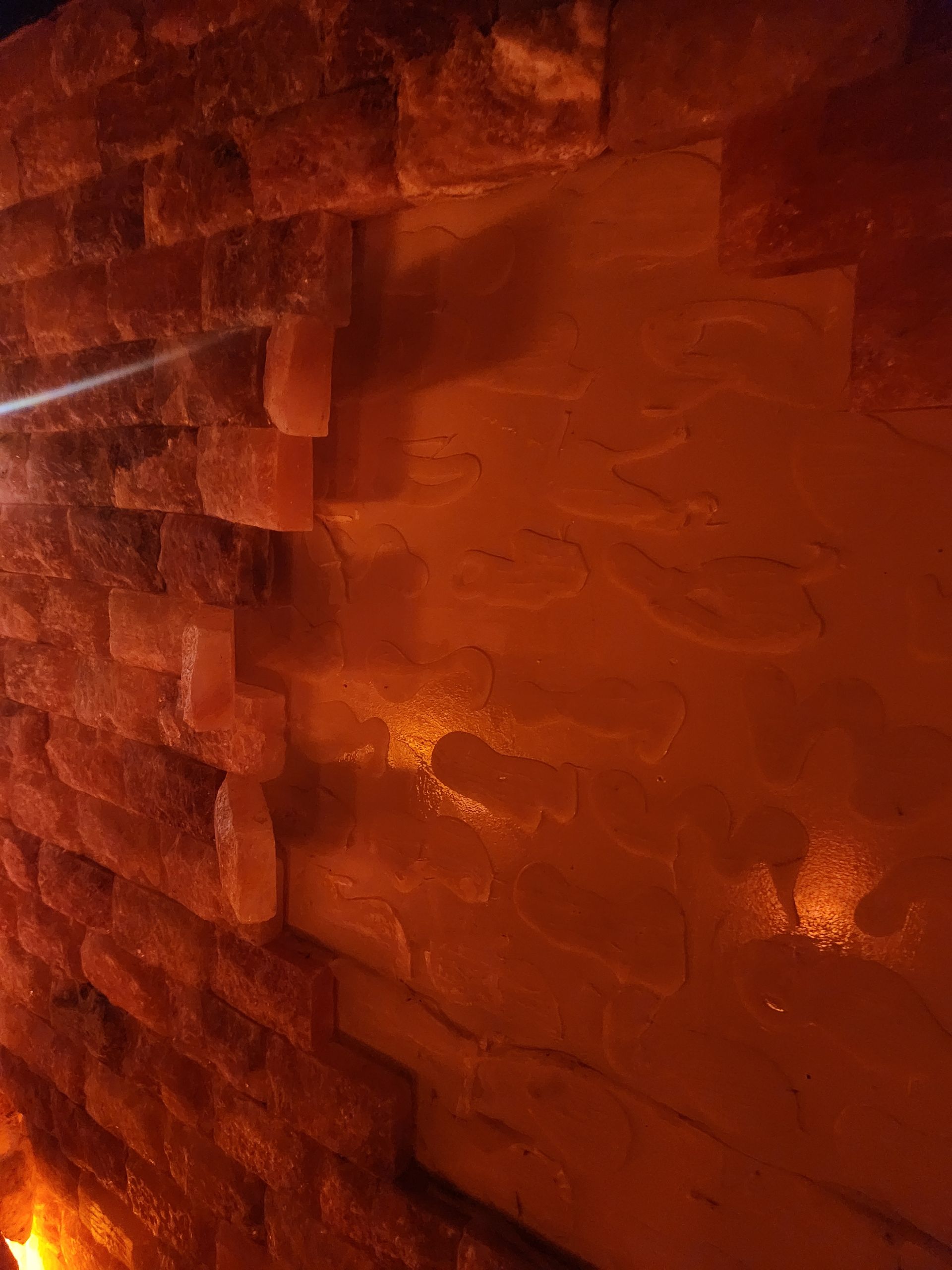 Salt rock wall with orange and brown hues, illuminated by warm light.