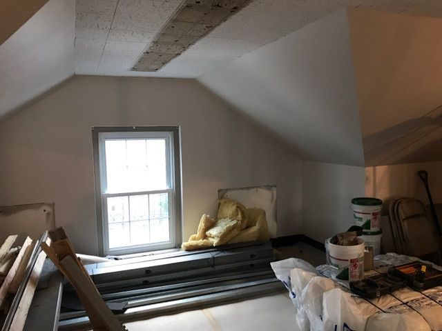 A room with a window and a bucket of paint