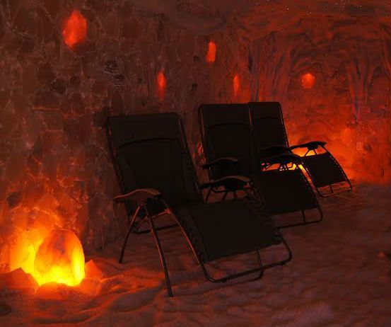 A couple of chairs are sitting in a salt room with a lamp.