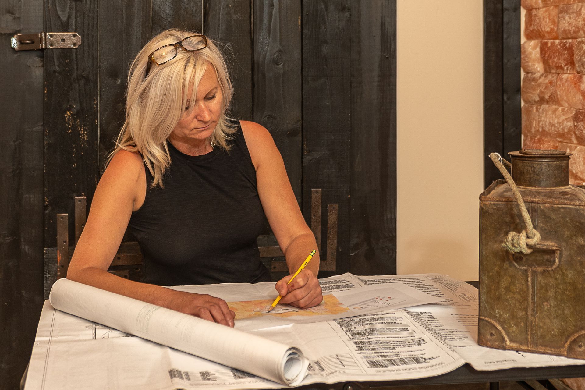 A woman is sitting at a table writing on a piece of paper.