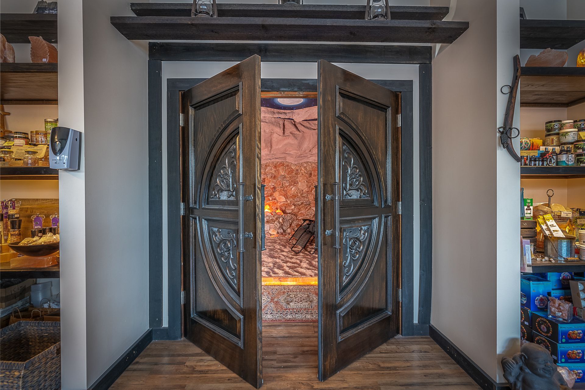 A large wooden door is open in a Salt cave with shelves.