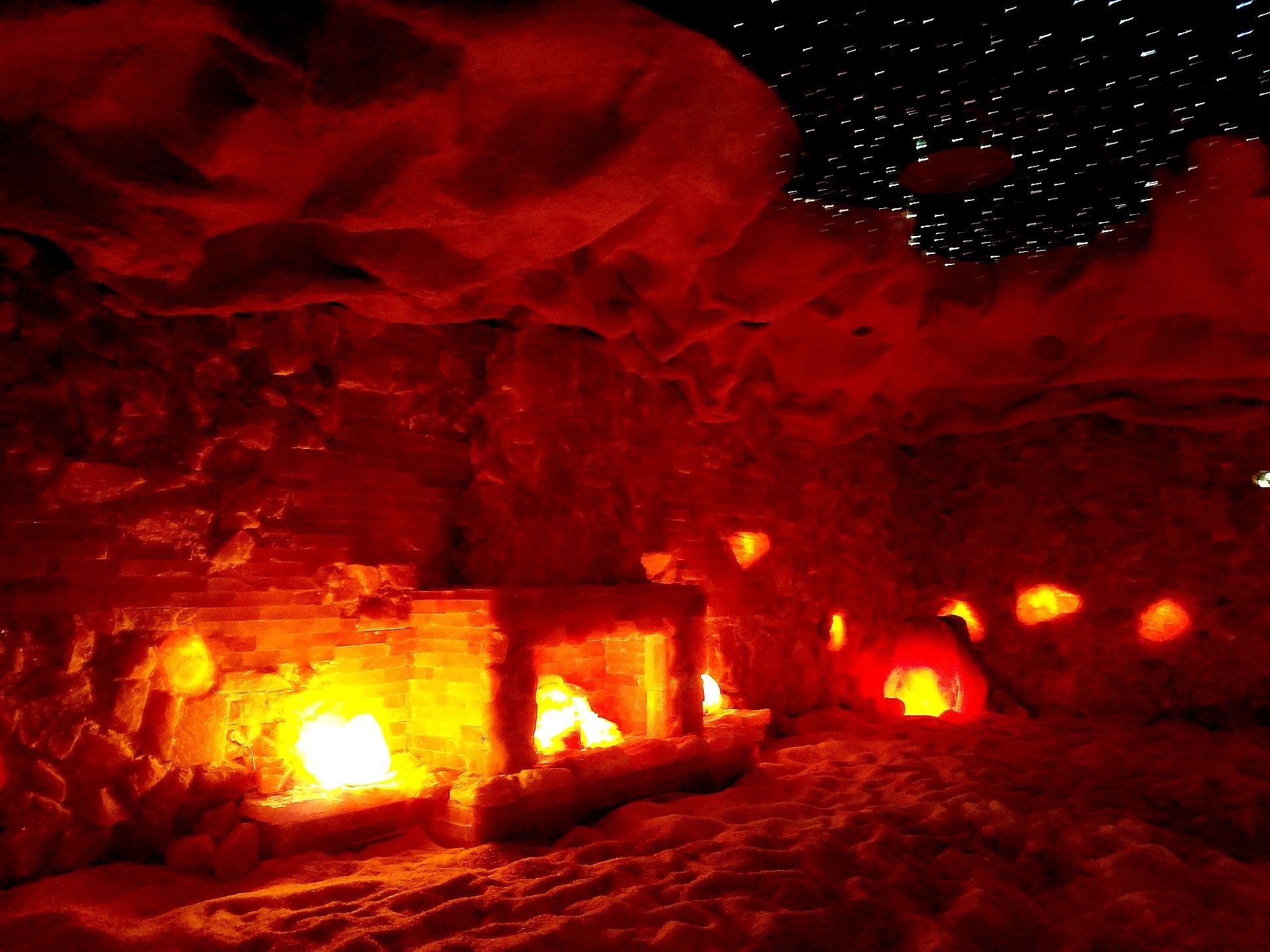 A fiery red cave with a glowing fireplace and carved lanterns; night sky with stars visible.