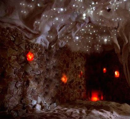 Cave interior with glowing orange orbs on walls and starry ceiling.