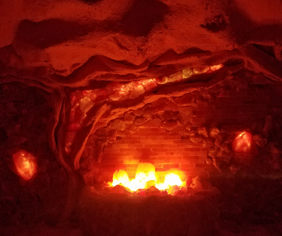 Glowing red cave with a fire at the bottom. The walls are textured and orange crystals dot the space.