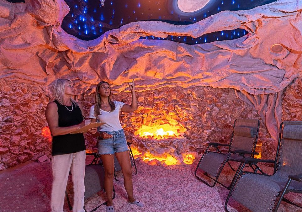 Two women are standing in a cave looking up at the ceiling.