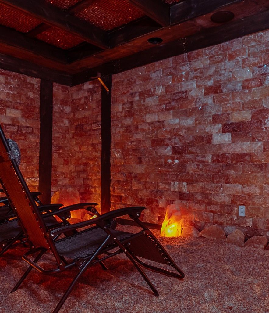 Salt room with recliner chairs, pink salt brick walls, dim lighting.