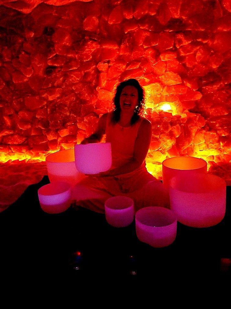 A woman is sitting in a cave holding a pink bowl.