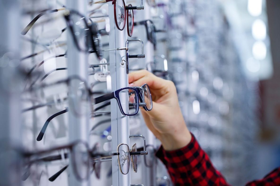 Une personne tient une paire de lunettes dans un magasin.