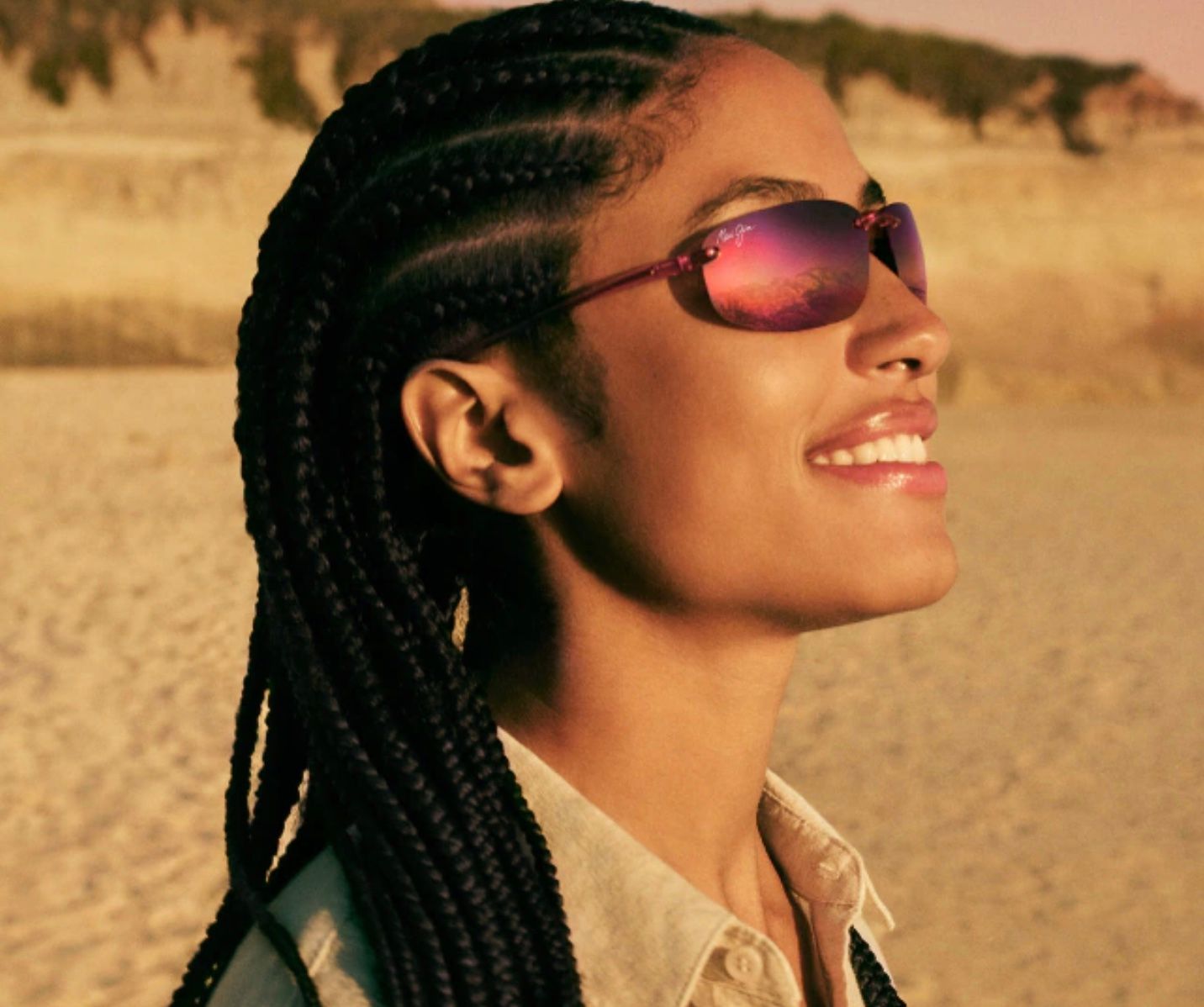 Une femme portant des lunettes de soleil et des boucles d'oreilles se tient devant un mur noir.