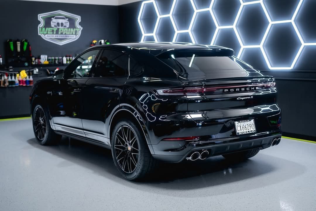 Black SUV parked in a garage with hexagon-shaped LED lights on the wall.