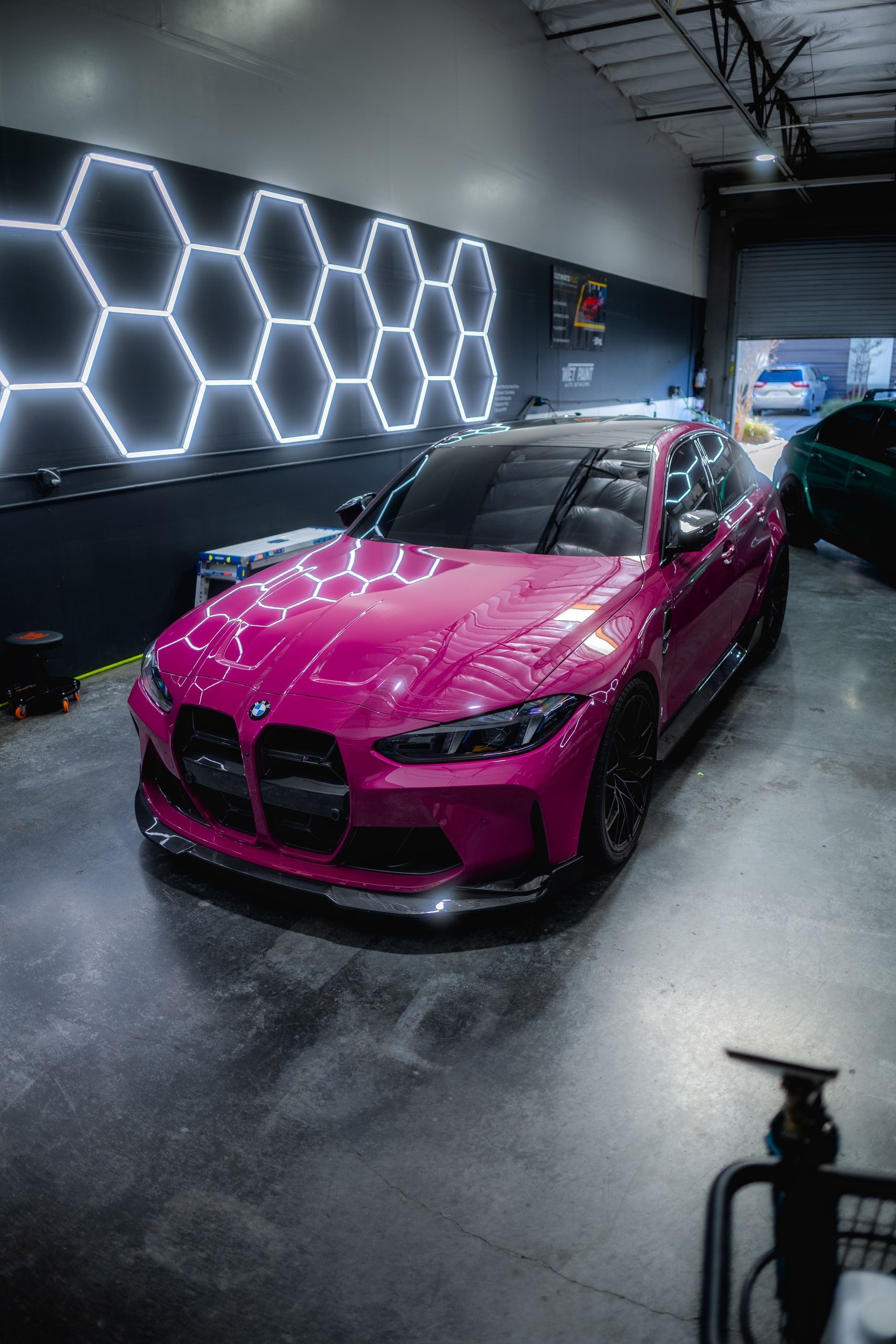 Pink BMW sports car in a garage with hexagon lights on the wall.