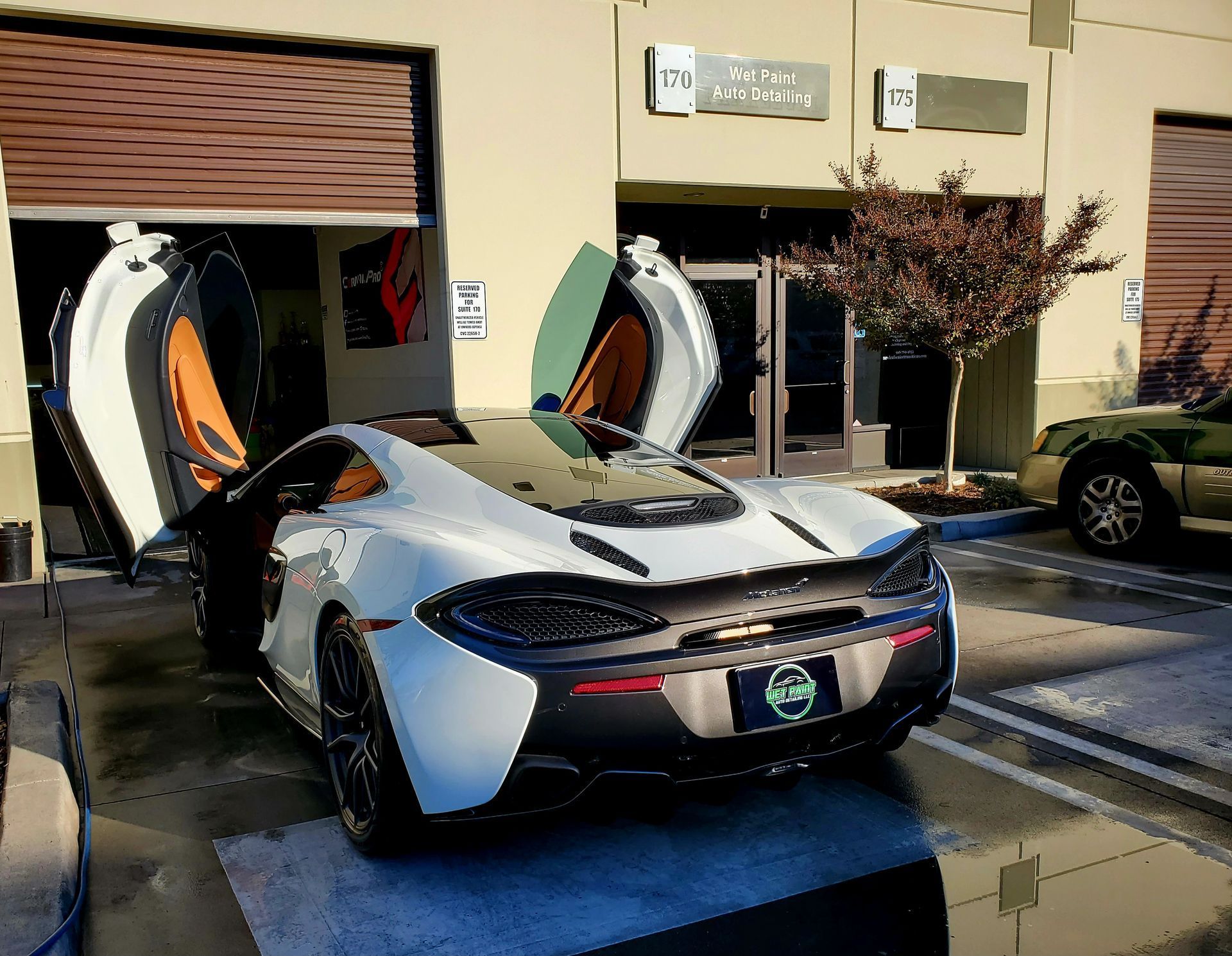 A white sports car is parked in front of a building with its doors open