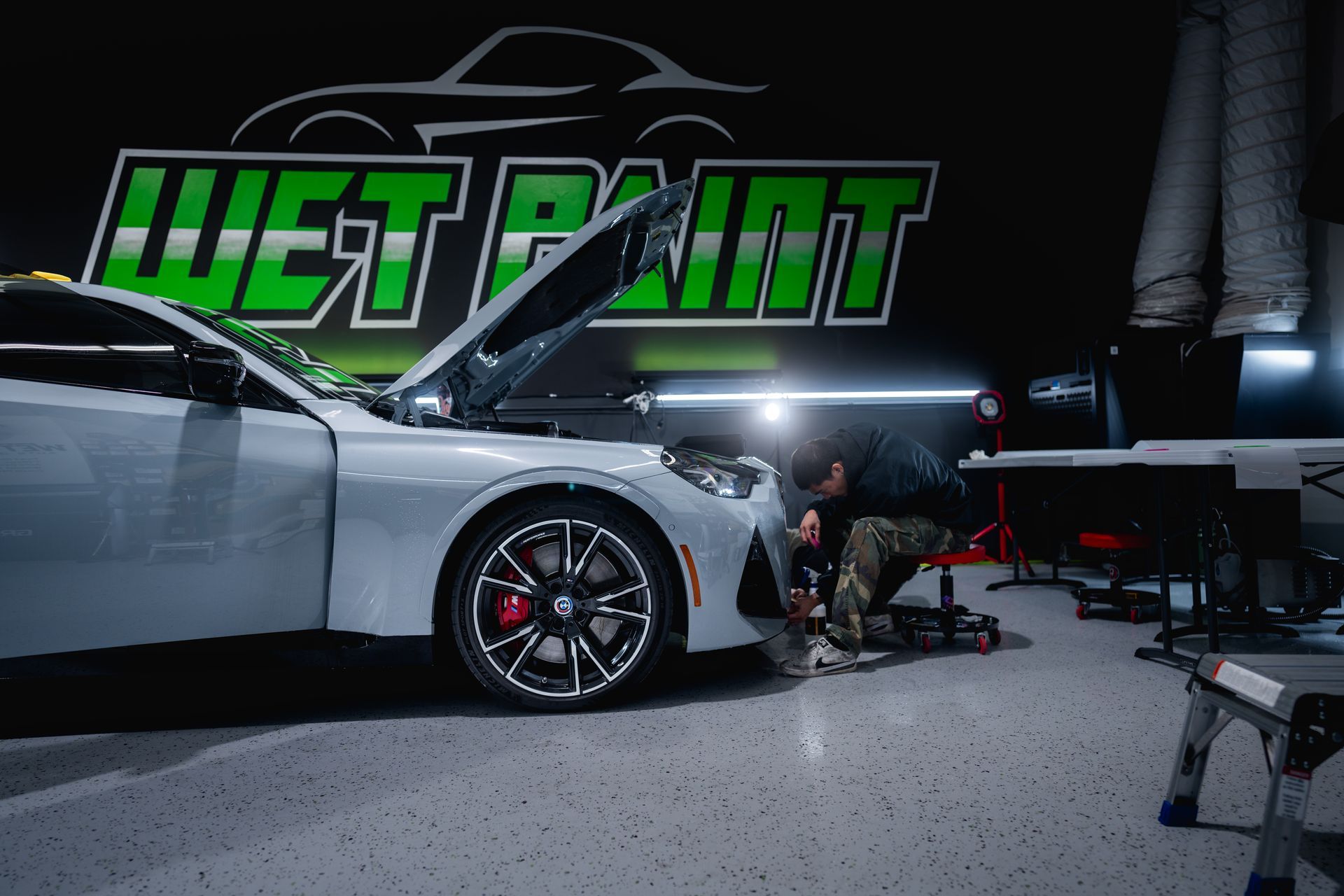 A person working on a white car in a garage with a 