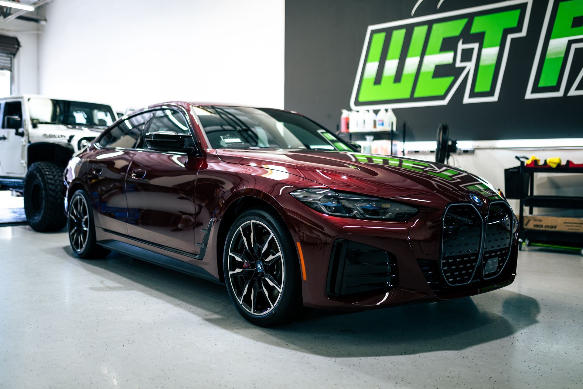 Red BMW car inside a garage. A white Jeep is visible in the background.