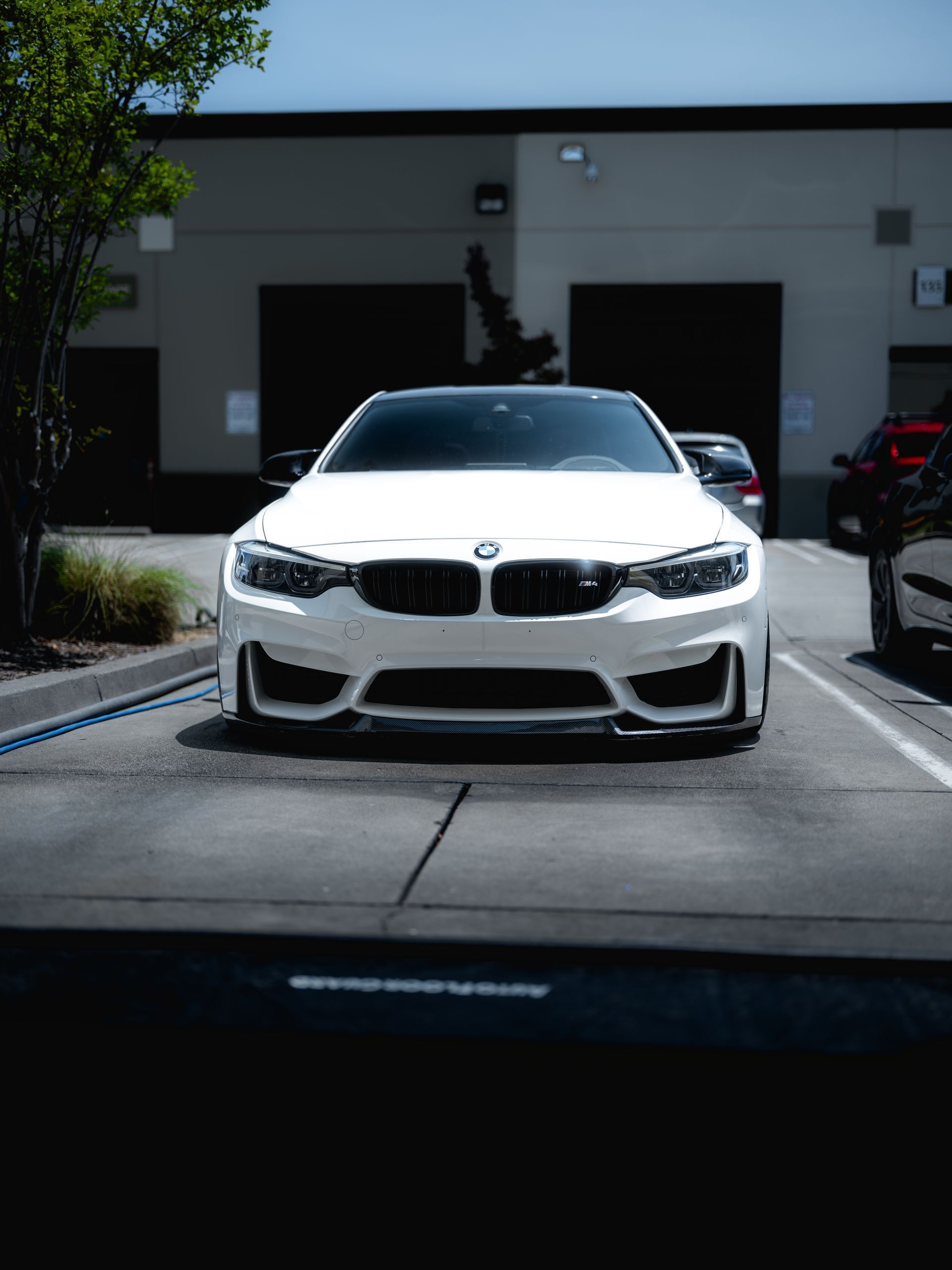 White BMW sports car parked in front of a building on a sunny day.