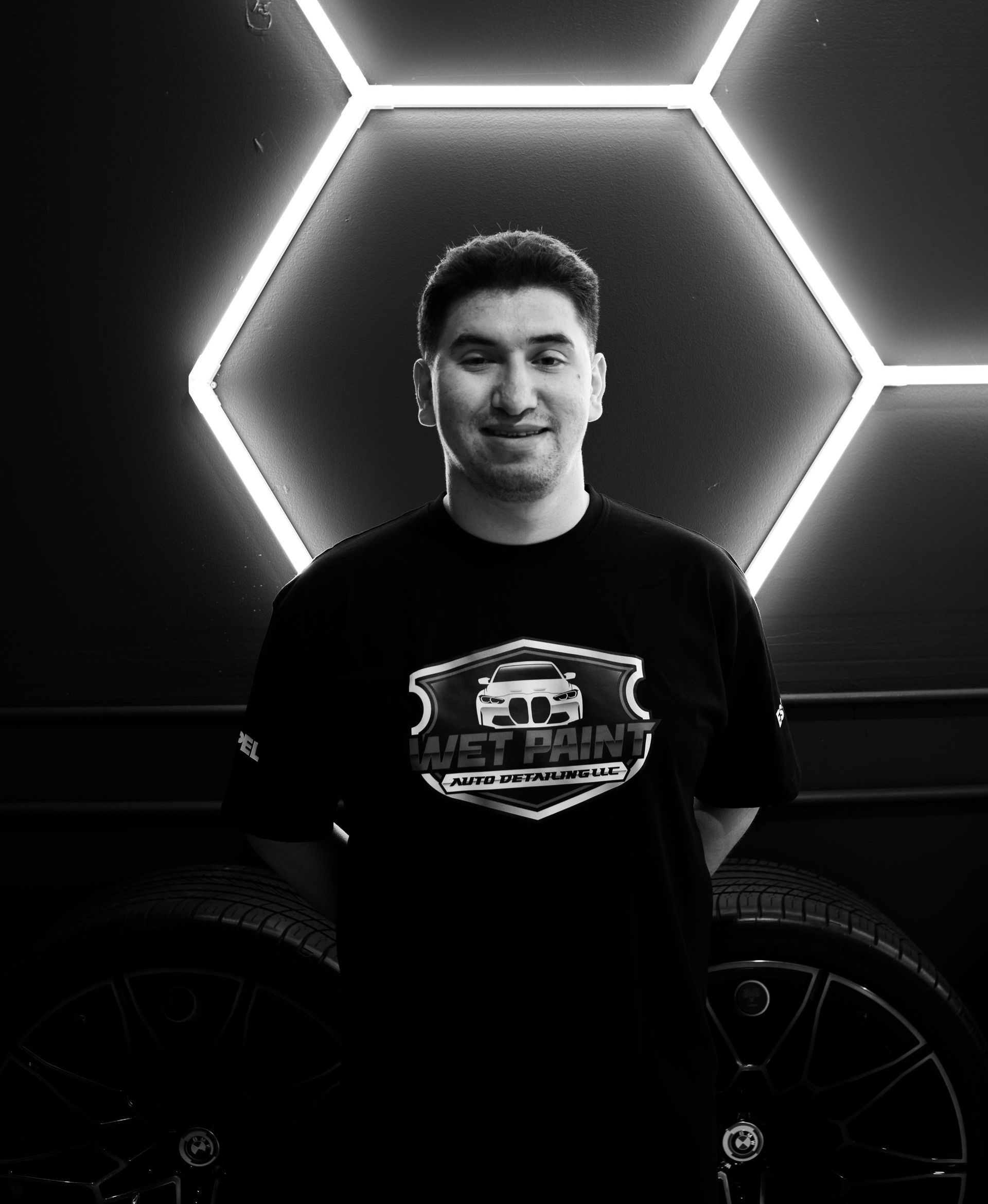A man is standing in front of a car in a black and white photo.