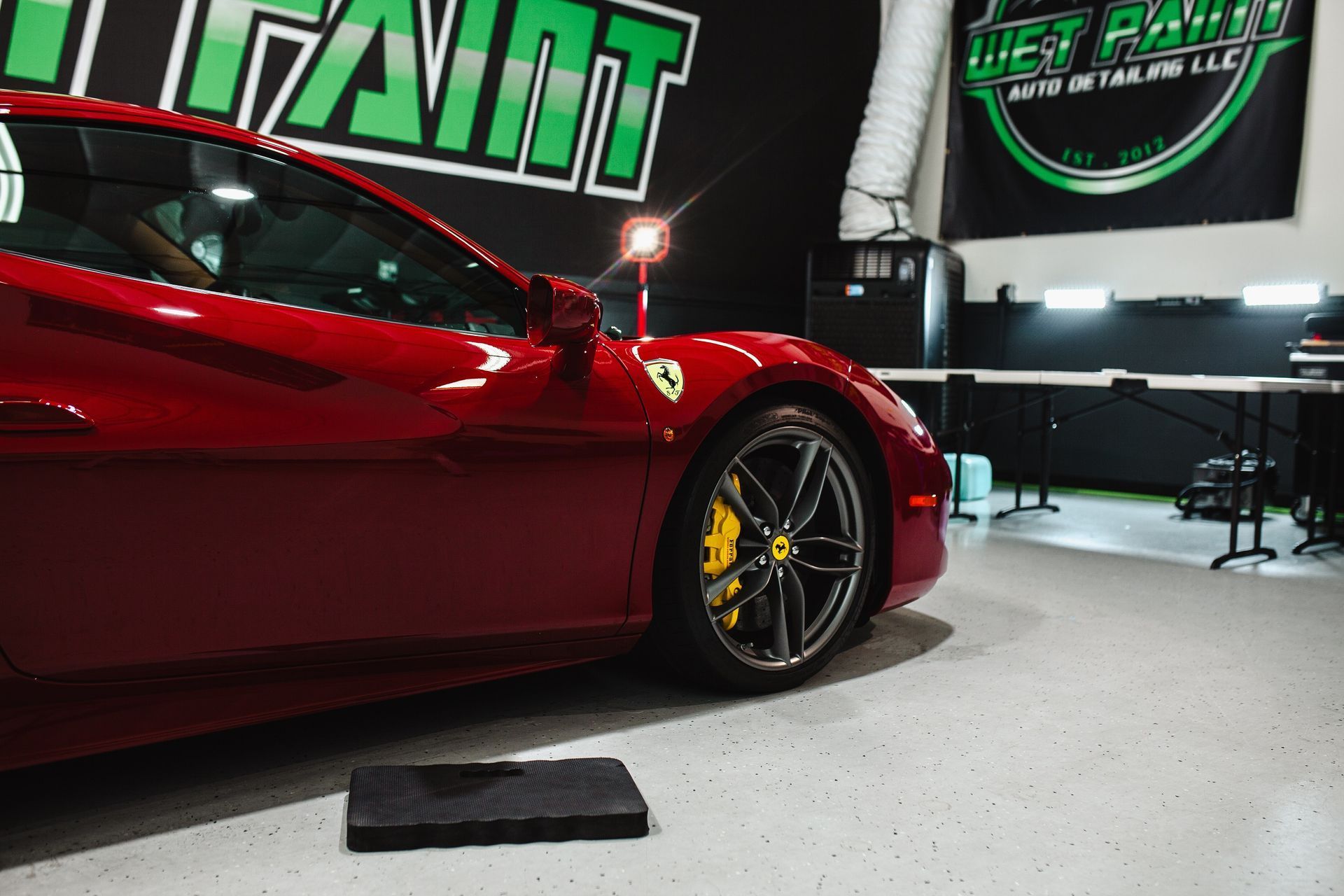 A red sports car is parked in front of a sign that says west point