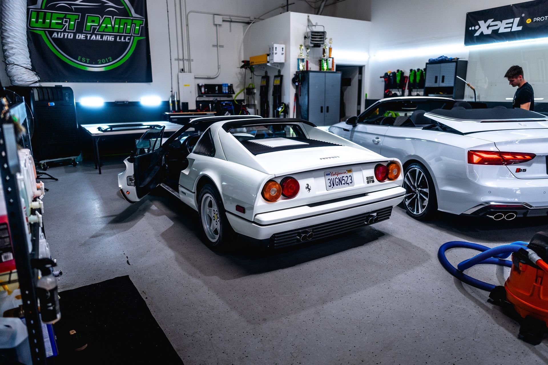 Two white sports cars are parked in a garage.
