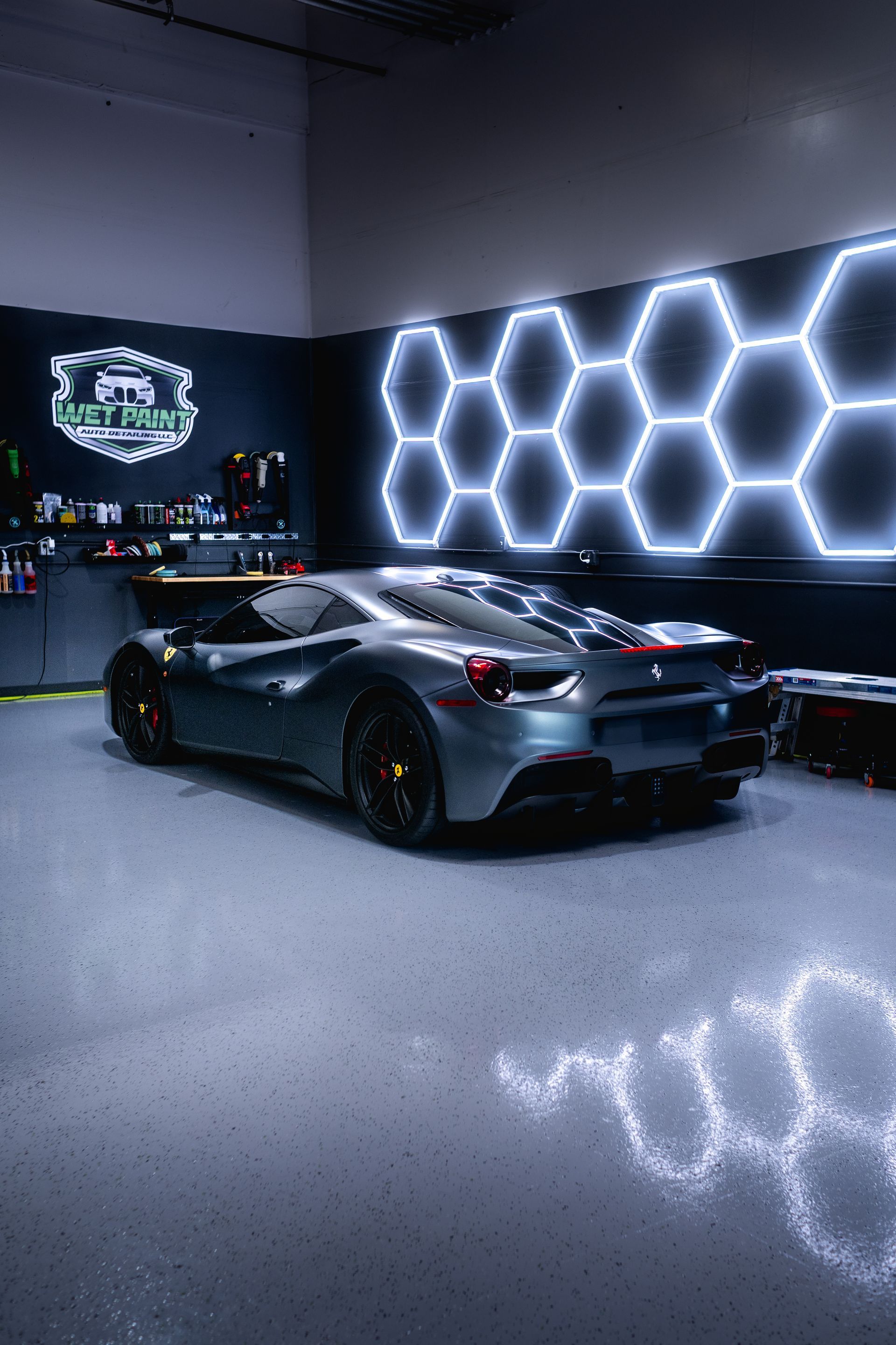 A car is parked in a garage with honeycomb lights on the wall.