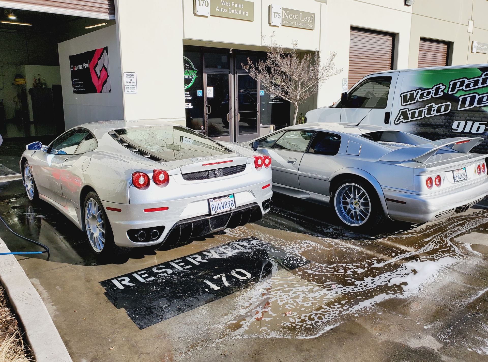 Two sports cars are parked in front of a car wash
