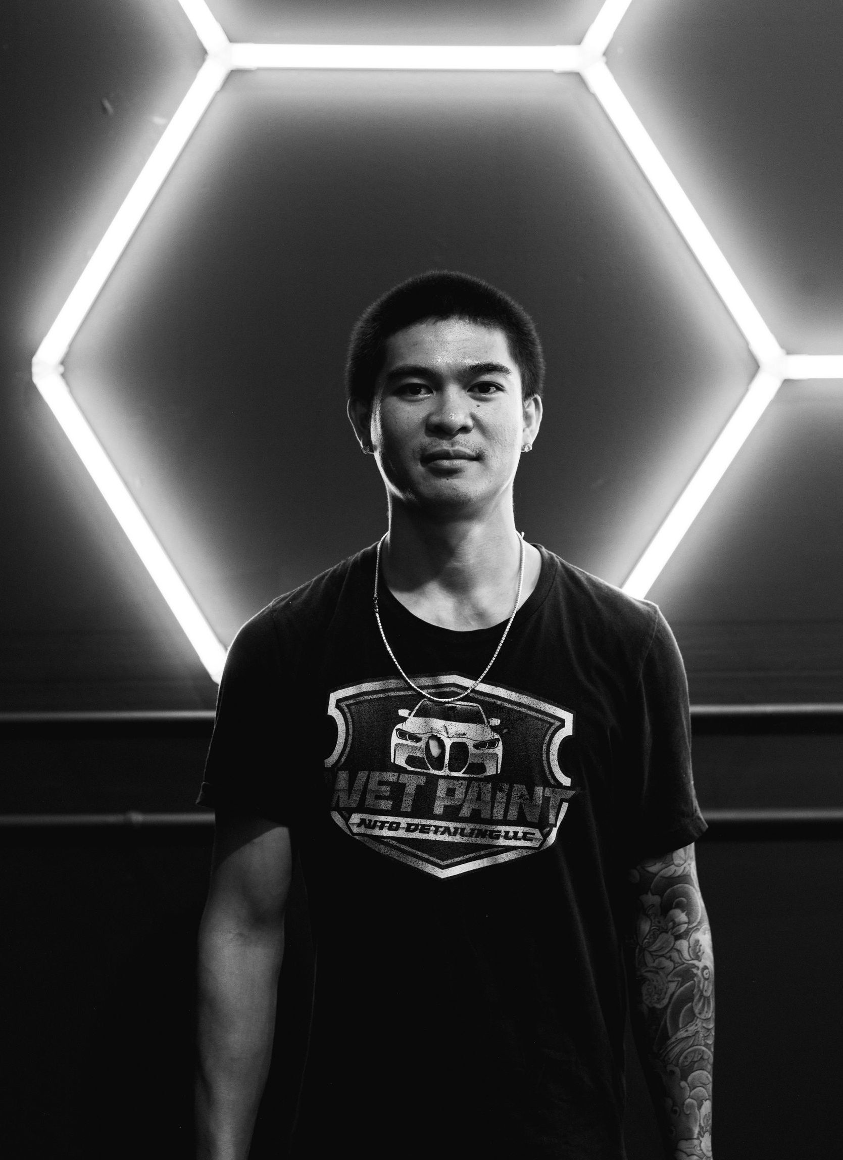 A man in a black shirt is standing in front of a wall with lights on it.