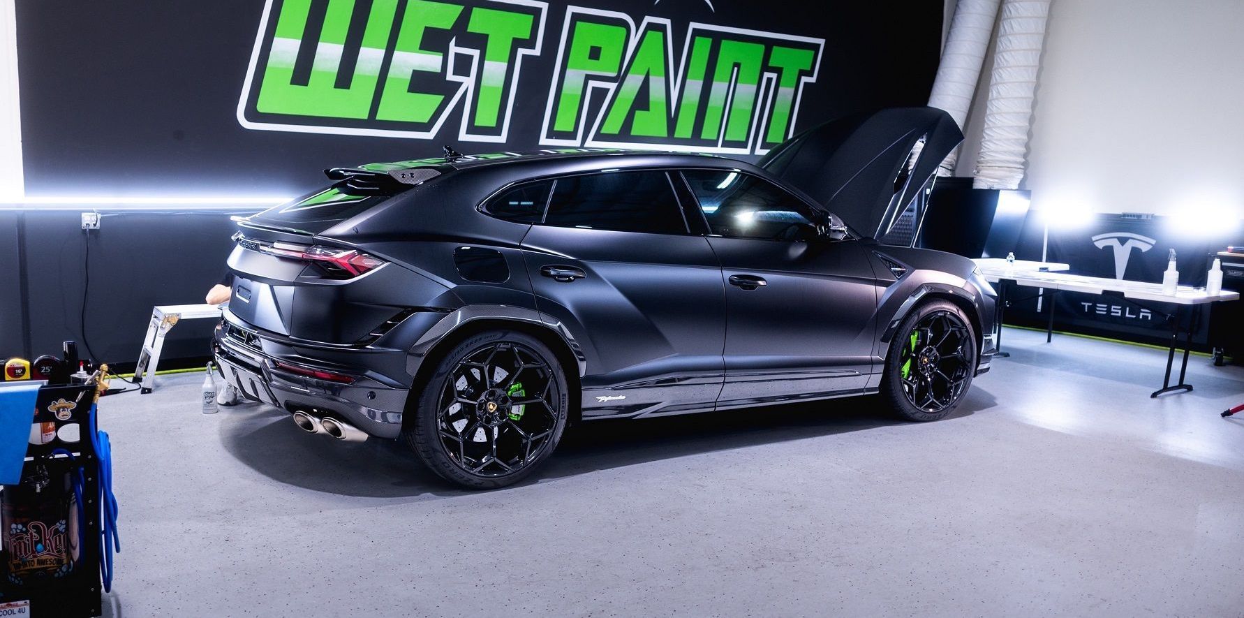 A car is parked in a garage with the hood open.