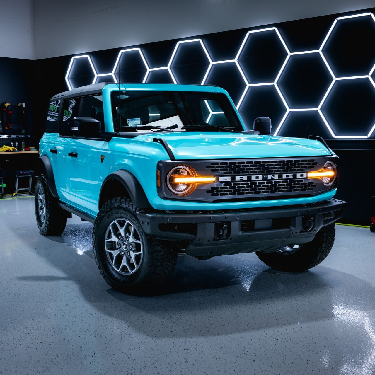 Pink Tesla in a garage with black accents and honeycomb lights.