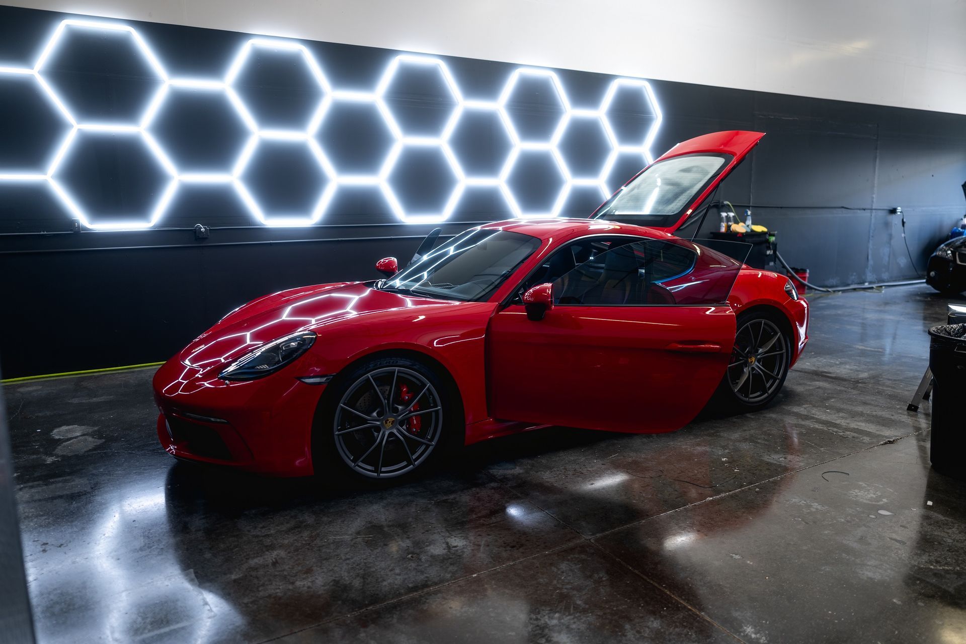A red sports car is parked in a garage with its hood up.