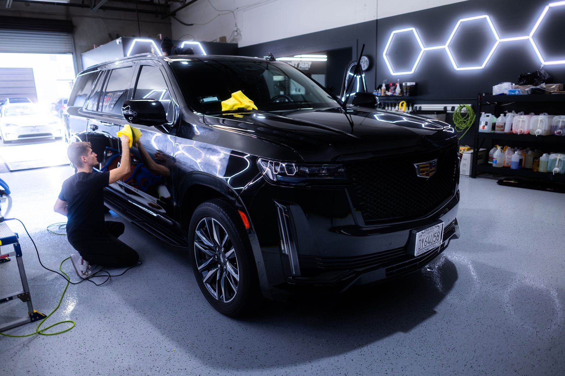 A man is cleaning a black suv in a garage.