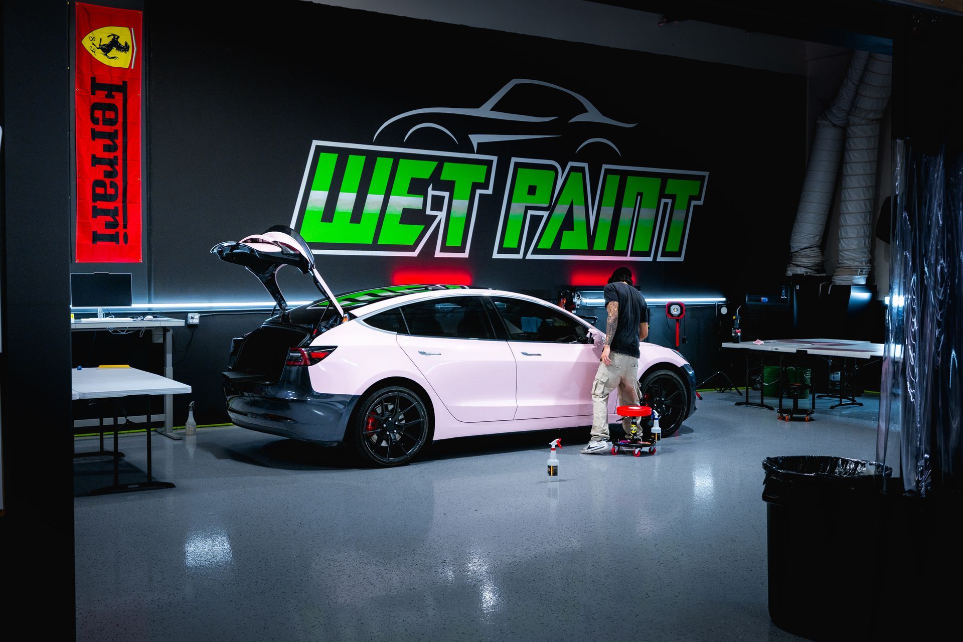 Man working on a pink car inside a garage with
