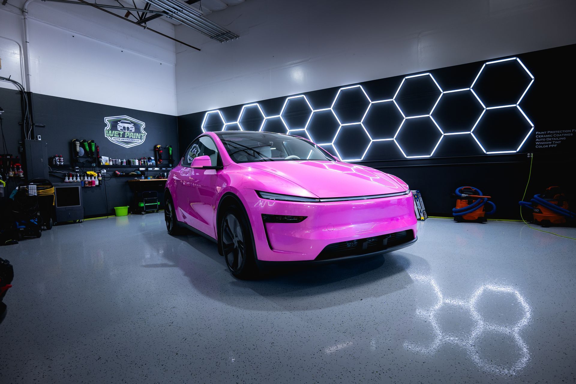 Pink car in a garage with hexagonal neon lights.