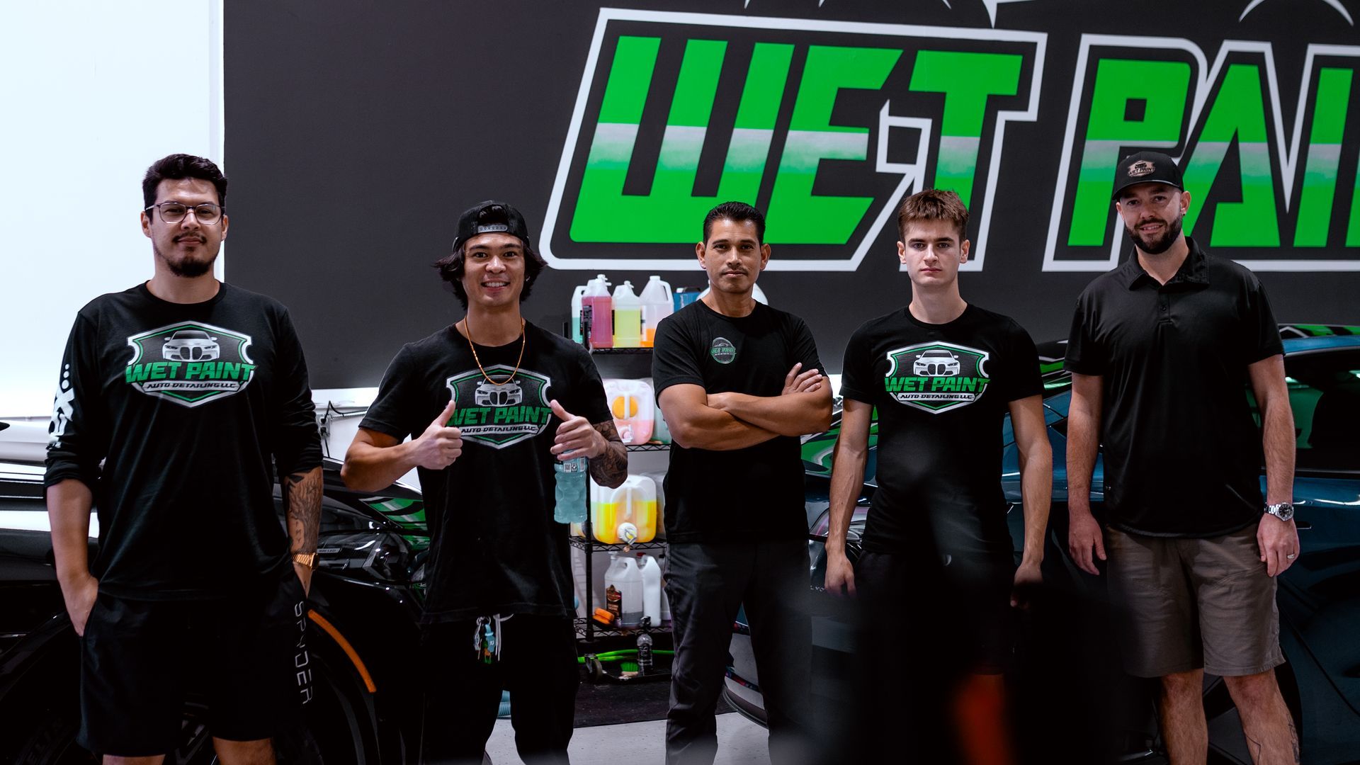 A group of men are standing in front of a wet paint sign.