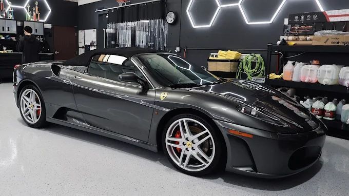 Dark gray Ferrari F430 Spider inside Wet Paint garage showcasing a glossy ceramic coating finish