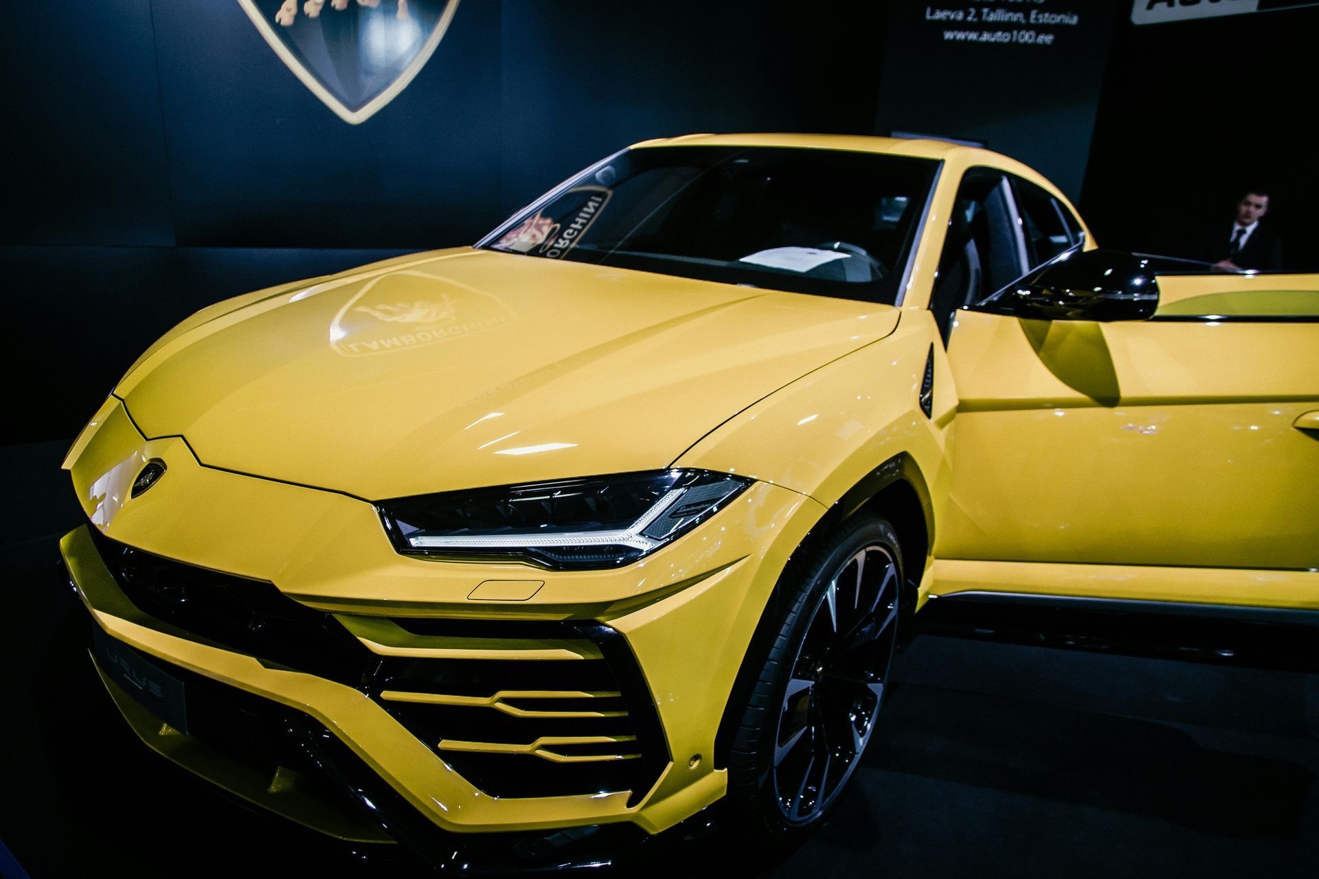 Yellow Lamborghini Urus SUV with door open, indoors.